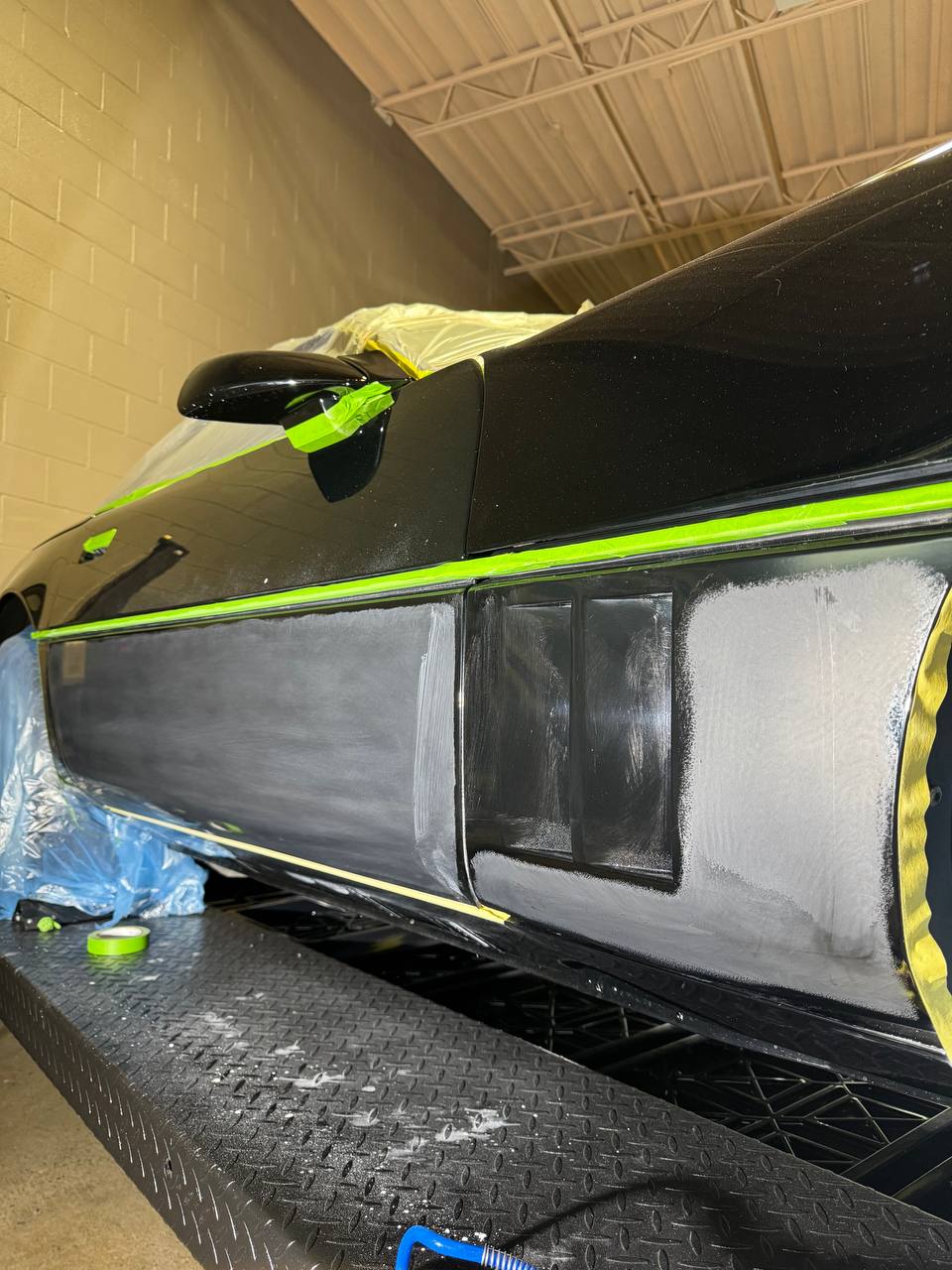 Black Corvette C4 undergoing detailing preparation with green tape