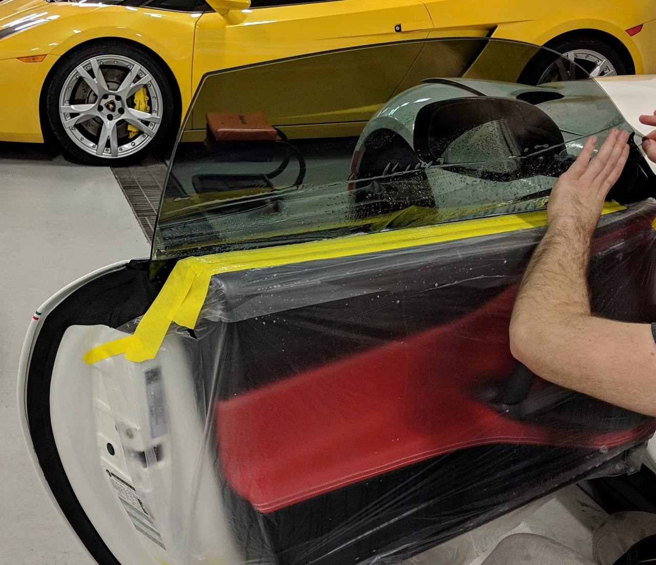 Car window film application with a yellow Lamborghini in the background