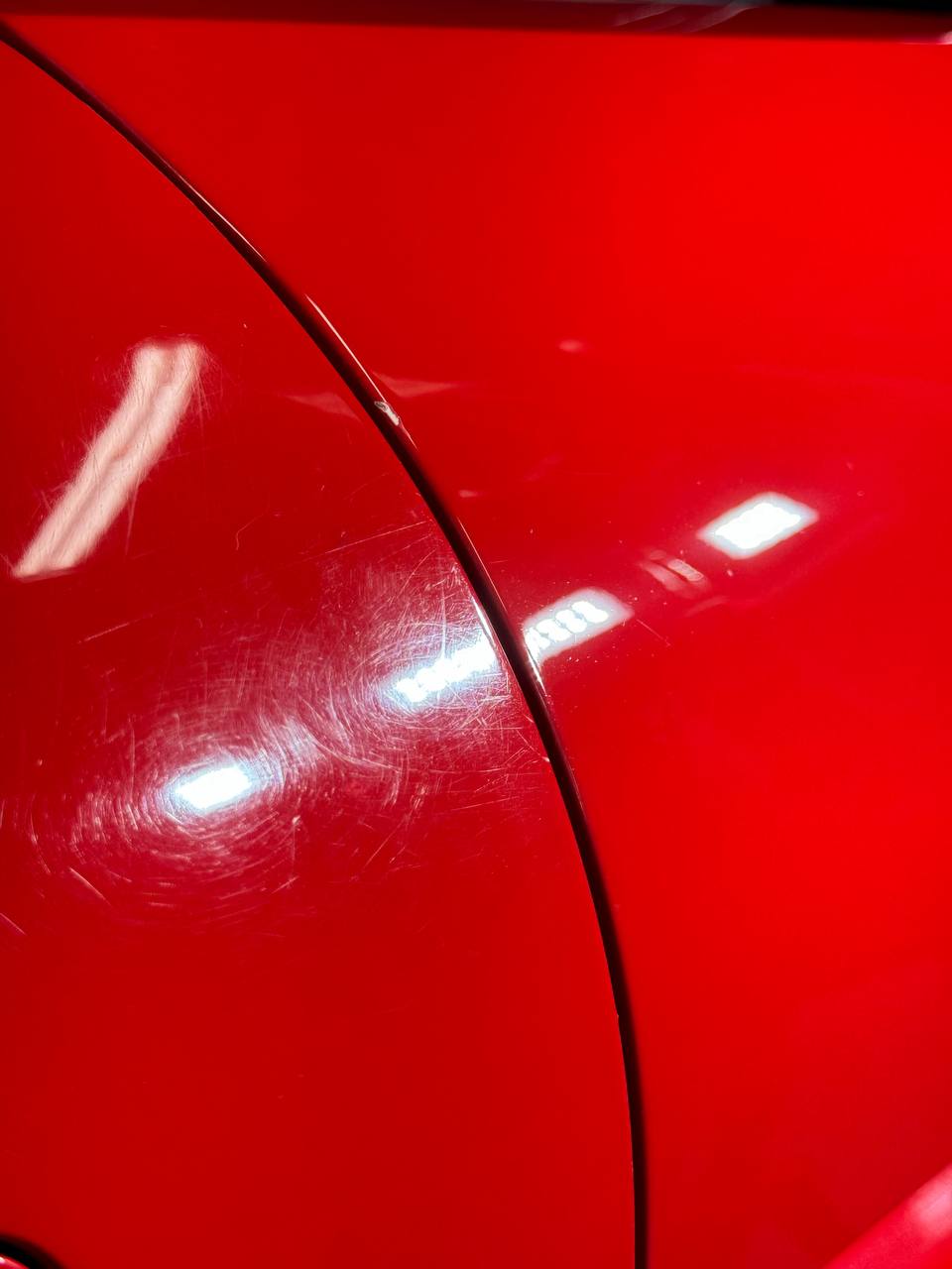 Red car with severe swirl marks before paint correction