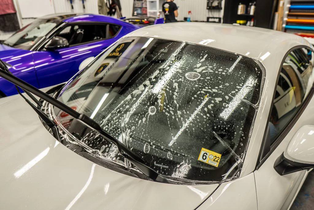 White car windshield being prepped for tint or film application